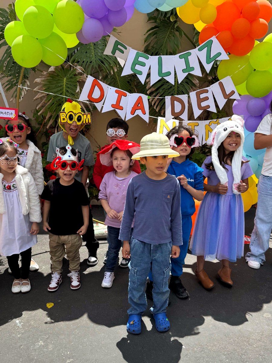 Niños de la iglesia celebrando el Día del Niño bajo un arco de globos.